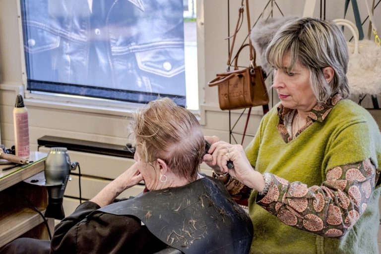 La coiffeuse est en train de couper les cheveux d'une cliente.
